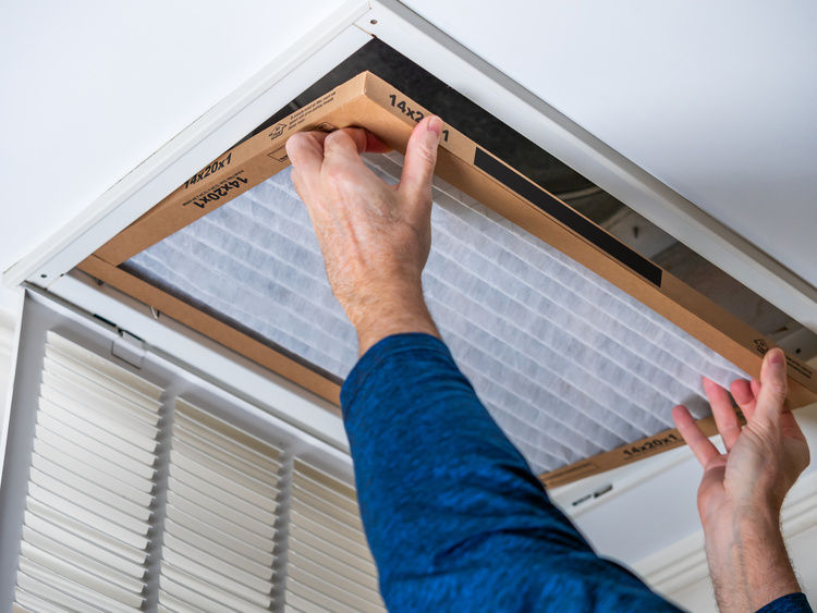 A man changing the AC filter |Blog | Greystar